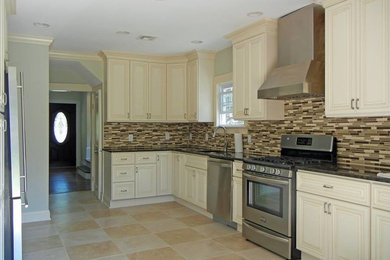 Kitchen - mid-sized contemporary travertine floor kitchen idea in New York with an undermount sink, raised-panel cabinets, beige cabinets, granite countertops, multicolored backsplash, glass tile backsplash and stainless steel appliances