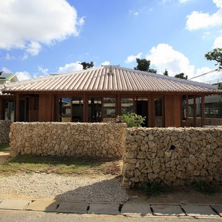 他の地域のアジアンスタイルのおしゃれな住宅の外観 (木材サイディング、茶色い外壁、寄棟屋根、瓦屋根) の写真