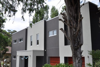 Design ideas for a large modern two-storey stucco grey exterior in Sydney with a flat roof.