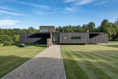 This is an example of a mid-sized contemporary two-storey black house exterior in Hampshire with wood siding and a flat roof.