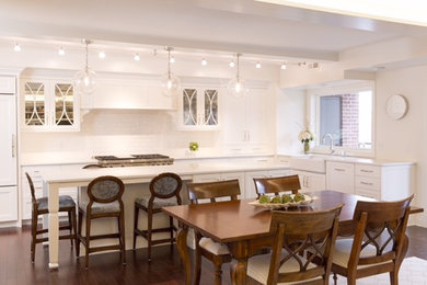 Inspiration for a large transitional u-shaped dark wood floor eat-in kitchen remodel in Other with a farmhouse sink, flat-panel cabinets, white cabinets, soapstone countertops, white backsplash, subway tile backsplash, stainless steel appliances and an island
