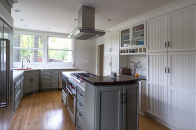 Mid-sized transitional u-shaped medium tone wood floor and brown floor open concept kitchen photo in Cedar Rapids with an undermount sink, recessed-panel cabinets, white cabinets, solid surface countertops, stainless steel appliances and an island