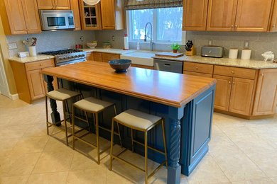 Design ideas for a mid-sized traditional l-shaped eat-in kitchen in Providence with a farmhouse sink, raised-panel cabinets, blue cabinets, wood benchtops, grey splashback, stainless steel appliances, with island, multi-coloured floor and brown benchtop.