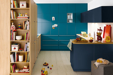 Small modern galley enclosed kitchen in Surrey with flat-panel cabinets, blue cabinets, laminate countertops, light hardwood flooring and a breakfast bar.