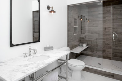 Mid-sized industrial 3/4 bathroom in Detroit with a two-piece toilet, porcelain tile, white walls, ceramic floors, an undermount sink, marble benchtops, white floor, a hinged shower door, white benchtops, a shower seat, a single vanity and a freestanding vanity.
