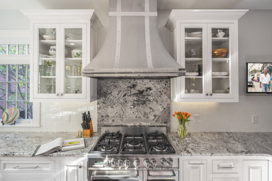Inspiration for a mid-sized transitional l-shaped eat-in kitchen in Boston with a farmhouse sink, raised-panel cabinets, white cabinets, granite benchtops, white splashback, subway tile splashback, stainless steel appliances, medium hardwood floors, a peninsula and brown floor.