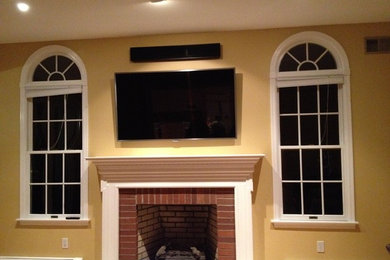 Inspiration for a mid-sized timeless open concept family room remodel in New York with yellow walls, a standard fireplace, a brick fireplace and a wall-mounted tv