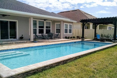 Design ideas for a mid-sized traditional backyard rectangular pool in Jacksonville with concrete pavers.