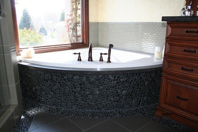 Example of a mid-sized classic master ceramic tile pebble tile floor and gray floor bathroom design in Other with beige walls, dark wood cabinets and a hinged shower door
