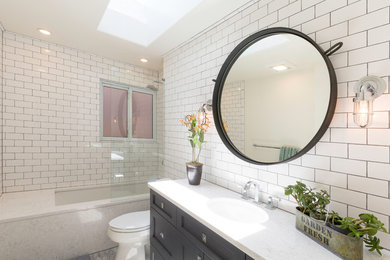 Photo of a mid-sized contemporary bathroom in Denver with shaker cabinets, black cabinets, an undermount tub, a shower/bathtub combo, a two-piece toilet, white tile, subway tile, an undermount sink, marble benchtops and an open shower.