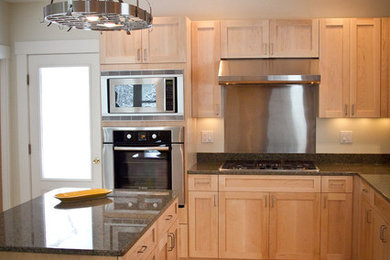 Example of a large minimalist u-shaped light wood floor eat-in kitchen design in Portland Maine with shaker cabinets, light wood cabinets, granite countertops, an island and stainless steel appliances