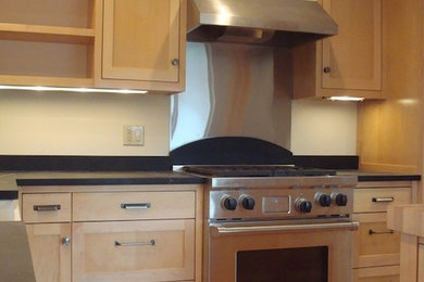 Example of a mid-sized l-shaped medium tone wood floor eat-in kitchen design in Other with medium tone wood cabinets, solid surface countertops, stainless steel appliances and an island