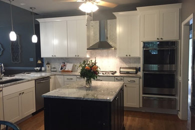 Example of a mid-sized transitional l-shaped medium tone wood floor and brown floor eat-in kitchen design in Atlanta with an undermount sink, shaker cabinets, white cabinets, granite countertops, multicolored backsplash, marble backsplash, stainless steel appliances, an island and multicolored countertops
