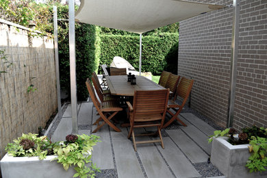 Patio - large contemporary side yard stone patio idea in Toronto with a pergola
