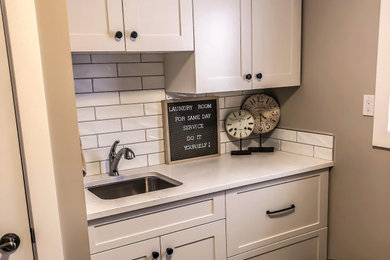 Example of a mid-sized transitional galley ceramic tile and brown floor dedicated laundry room design in Other with an undermount sink, shaker cabinets, white cabinets, white backsplash, subway tile backsplash, gray walls, a side-by-side washer/dryer and white countertops
