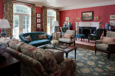 Inspiration for a large eclectic enclosed medium tone wood floor living room library remodel in DC Metro with red walls, a standard fireplace, a wall-mounted tv and a plaster fireplace