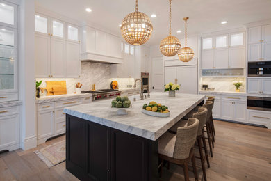 Example of a huge transitional l-shaped light wood floor and beige floor eat-in kitchen design in San Francisco with a farmhouse sink, shaker cabinets, white cabinets, marble countertops, white backsplash, stone slab backsplash, paneled appliances, an island and white countertops