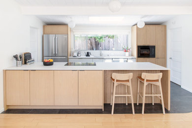 Inspiration for a mid-sized 1950s galley exposed beam kitchen remodel in San Francisco with flat-panel cabinets, light wood cabinets, quartz countertops, stainless steel appliances and white countertops