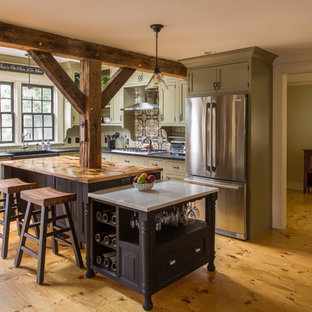 Large country l-shaped kitchen pantry in Boston with a farmhouse sink, beaded inset cabinets, green cabinets, soapstone benchtops, brown splashback, ceramic splashback, stainless steel appliances, light hardwood floors and with island.