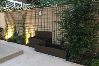 Modelo de patio moderno pequeño sin cubierta en patio delantero con fuente y suelo de baldosas