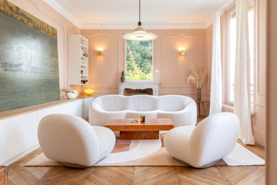 Réalisation d'un salon beige et blanc haussmannien avec un mur rose, parquet clair, une cheminée standard et un manteau de cheminée en pierre.