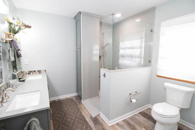 Inspiration for a mid-sized master bathroom in Other with shaker cabinets, green cabinets, an open shower, a two-piece toilet, grey walls, vinyl floors, an integrated sink, solid surface benchtops, brown floor, an open shower, grey benchtops, a double vanity and a built-in vanity.