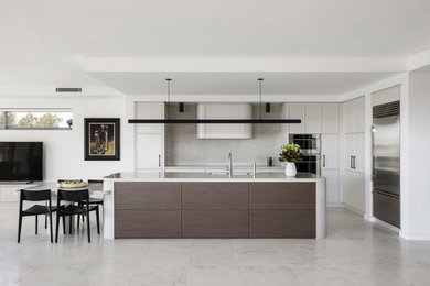 Design ideas for an expansive modern l-shaped open plan kitchen in Sydney with an undermount sink, shaker cabinets, beige cabinets, solid surface benchtops, beige splashback, stainless steel appliances, marble floors, with island, white floor and beige benchtop.