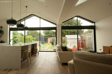 Medium sized contemporary l-shaped kitchen/diner in London with quartz worktops, porcelain flooring, an island, multicoloured worktops and a vaulted ceiling.