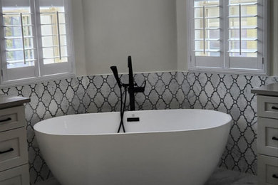 Пример оригинального дизайна: большая главная ванная комната в стиле неоклассика (современная классика) с фасадами в стиле шейкер, серыми фасадами, угловой ванной, серой плиткой, белыми стенами, мраморным полом, серым полом и напольной тумбой