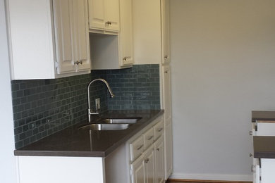 Enclosed kitchen - contemporary u-shaped dark wood floor enclosed kitchen idea in Los Angeles with an undermount sink, raised-panel cabinets, white cabinets, quartz countertops, blue backsplash, glass tile backsplash and stainless steel appliances