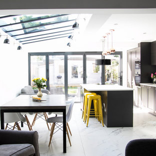 Design ideas for a medium sized contemporary galley kitchen/diner in London with a submerged sink, shaker cabinets, black cabinets, black appliances, an island, white floors and white worktops.