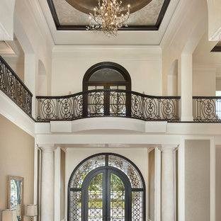 Новые идеи обустройства дома: огромное фойе в классическом стиле с бежевыми стенами, мраморным полом, двустворчатой входной дверью и металлической входной дверью