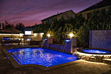 This is an example of a large traditional backyard rectangular lap pool in New York with a water feature and concrete pavers.