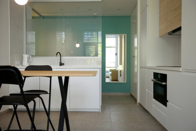 Inspiration för avskilda, små moderna kök, med släta luckor, vita skåp, bänkskiva i kvarts, klinkergolv i keramik och beiget golv