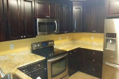 Example of a mid-sized classic u-shaped beige floor enclosed kitchen design in Charlotte with an undermount sink, raised-panel cabinets, dark wood cabinets, granite countertops and no island