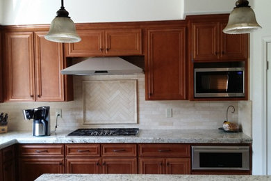 Inspiration for a timeless l-shaped porcelain tile kitchen pantry remodel in San Francisco with a double-bowl sink, raised-panel cabinets, light wood cabinets, beige backsplash, porcelain backsplash, stainless steel appliances and an island