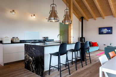 Inspiration for a small modern galley open plan kitchen in Other with a built-in sink, white cabinets, granite worktops, white splashback, glass sheet splashback, black appliances, an island and multicoloured worktops.