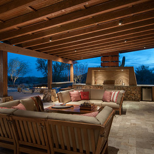 フェニックスの大きいサンタフェスタイルのおしゃれな裏庭のテラス (アウトドアキッチン、天然石敷き、張り出し屋根) の写真