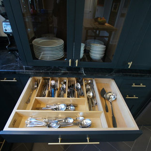 Design ideas for a mid-sized industrial l-shaped kitchen pantry in DC Metro with a farmhouse sink, flat-panel cabinets, grey cabinets, soapstone benchtops, stainless steel appliances, porcelain floors and with island.