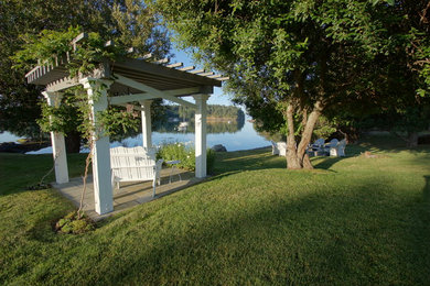 Example of a mid-sized beach style backyard stone patio design in Seattle with a fire pit and a gazebo