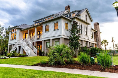 Large beach style white three-story mixed siding exterior home photo in Charleston with a metal roof