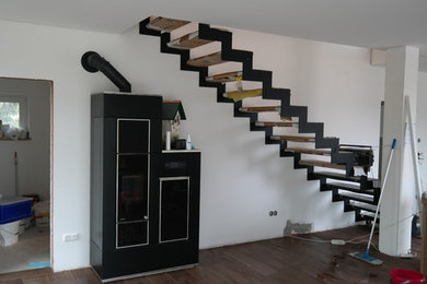 Mittelgroßes, Offenes Modernes Wohnzimmer mit weißer Wandfarbe, Keramikboden, Kaminofen, Kaminumrandung aus Metall, freistehendem TV und braunem Boden in München