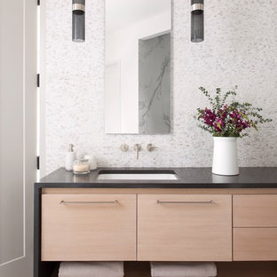 Esempio di una stanza da bagno moderna con ante lisce, ante in legno chiaro, piastrelle grigie, piastrelle bianche, piastrelle a mosaico, pareti multicolore, pavimento in laminato, lavabo sottopiano e top in superficie solida
