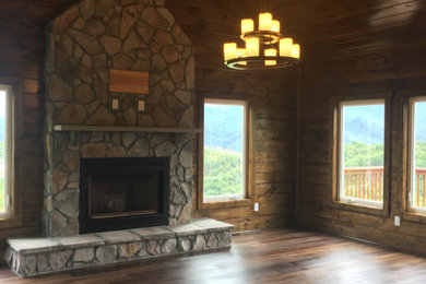 Example of an arts and crafts vaulted ceiling and wood wall living room design in Other with a stone fireplace