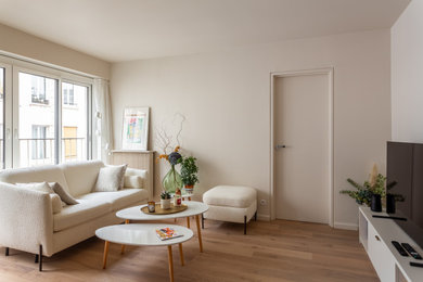 Cette image montre un petit salon beige et blanc minimaliste ouvert avec un mur beige, un sol en bois brun, aucune cheminée, un téléviseur indépendant et un sol marron.