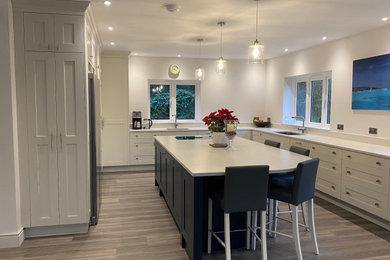 Example of a large minimalist u-shaped open concept kitchen design with shaker cabinets, solid surface countertops, an island and gray countertops