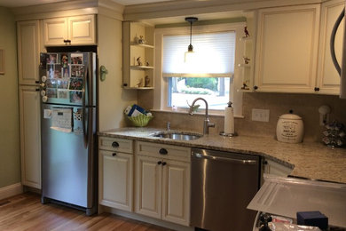 Example of a mid-sized classic l-shaped light wood floor enclosed kitchen design in Boston with an undermount sink, raised-panel cabinets, yellow cabinets, granite countertops, brown backsplash, ceramic backsplash, stainless steel appliances and no island