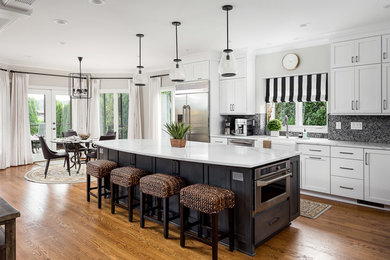 Transitional galley medium tone wood floor and brown floor eat-in kitchen photo in Louisville with a farmhouse sink, shaker cabinets, white cabinets, gray backsplash, mosaic tile backsplash, stainless steel appliances, an island and white countertops