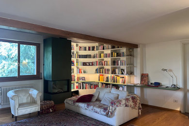Esempio di un soggiorno design aperto con libreria, pareti verdi, camino ad angolo, cornice del camino in cemento, soffitto in legno e parquet chiaro
