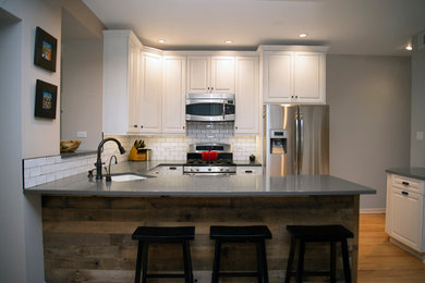 Example of a mountain style kitchen design in Chicago with a drop-in sink, shaker cabinets, white cabinets, quartzite countertops, white backsplash, ceramic backsplash and an island